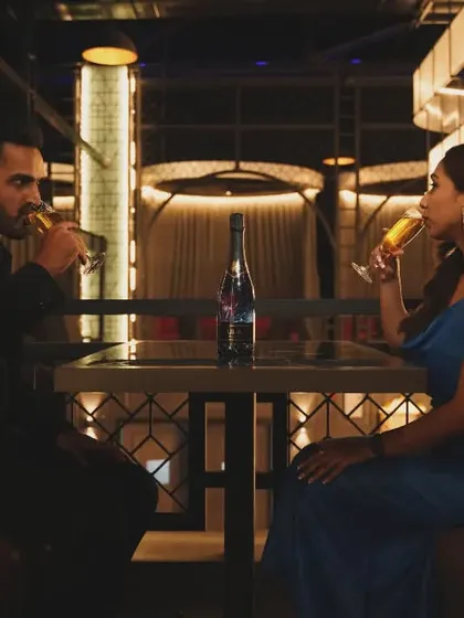 A silhouette-style shot of a couple enjoying drinks in a modern restaurant, creating a very cinematic and private feel for their pre-wedding album.