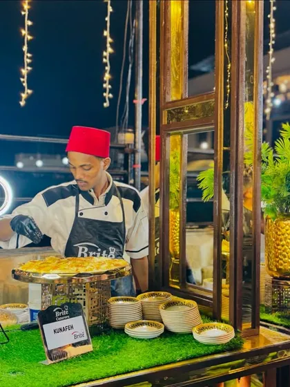 My chef, in a traditional red fez, prepares fresh Kunafeh, a classic Middle Eastern cheese pastry dessert.