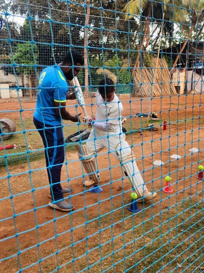 A coach adjusts a player's stance during net practice. This one-on-one attention is crucial for correcting technique and building the right muscle memory for consistent performance.