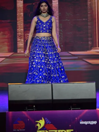 The model on the runway, where the vibrant blue of the lehenga and the polished makeup create a memorable stage presence.