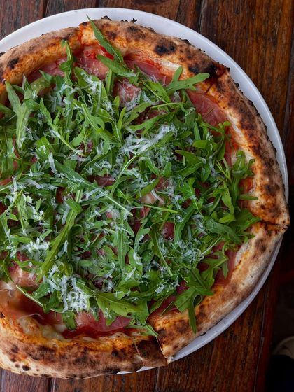 A beautiful overhead shot of our Parma Ham & Arugula pizza. The fresh greens are added after baking to maintain their crispness.