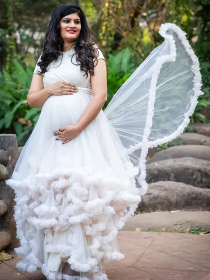 A solo portrait of the mom-to-be in a stunning white ruffled gown. The way the fabric flows creates a beautiful, angelic look.