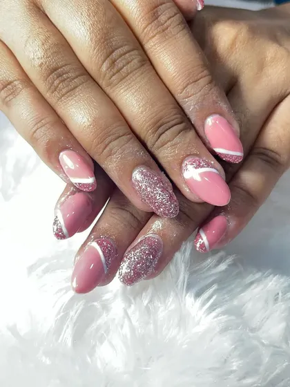 A close-up of the pink and glitter acrylic extensions. You can see the detail of the glitter and the crisp white lines that add a graphic element to the design.