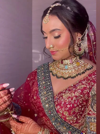 The bride adjusting her jewelry, a candid moment that shows off her intricate henna and beautiful makeup.