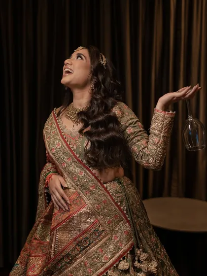 A bride laughing with a wine glass in hand, full of joy and ready to celebrate her Mehendi.