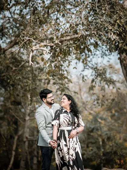 A lovely portrait of the couple looking at each other amidst the trees. The soft, natural light and green surroundings create a peaceful and romantic atmosphere.