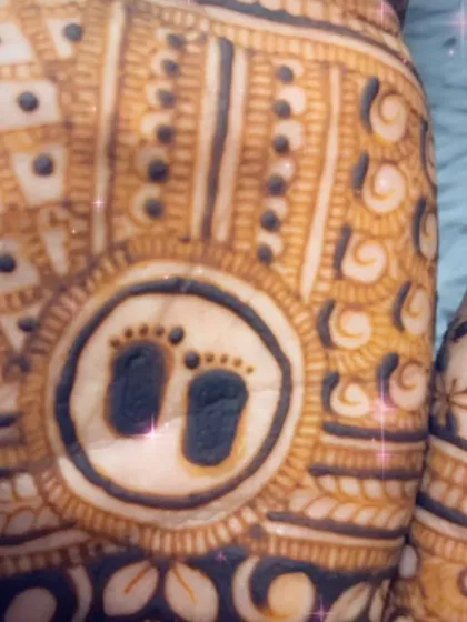 A close-up of the tiny baby feet motif, a very popular and sweet element to include in baby shower mehendi designs.