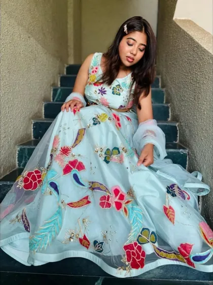 Seated on the steps, this image gives a great view of the artistic, hand-painted details that make this pastel lehenga so special and unique.