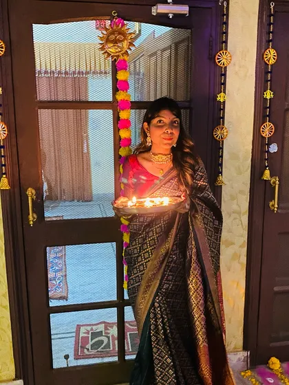 Celebrating Diwali with diyas in hand. For this look, I chose a classic black and gold woven saree with a contrasting red blouse. It's a sophisticated and timeless choice for the festival of lights.