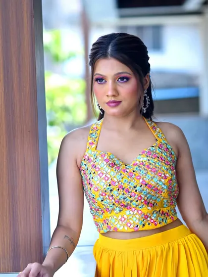 A model looking gorgeous in a yellow Haldi outfit. The makeup is modern and glamorous, with a focus on colorful, dramatic eyes.