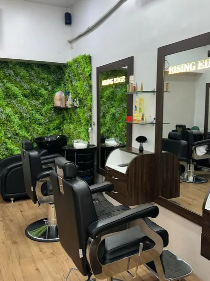 Another angle of the salon, highlighting the clean wooden floors, comfortable barber chairs, and the signature green accent wall.