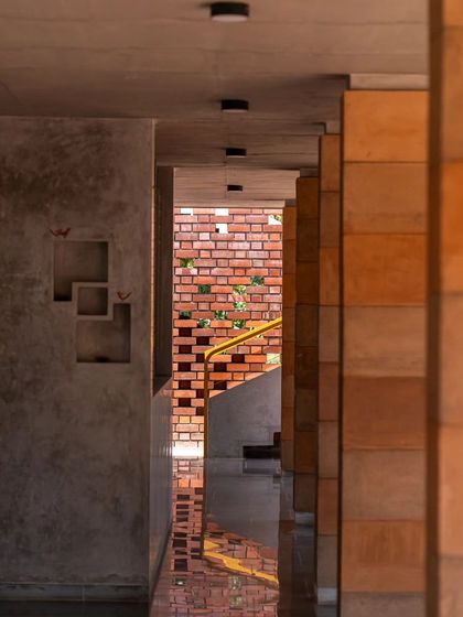 A view through the CSEB pillars towards the staircase. The design uses voids and solids to create intriguing sightlines and a sense of depth, with the perforated brick wall offering a hint of the space beyond.