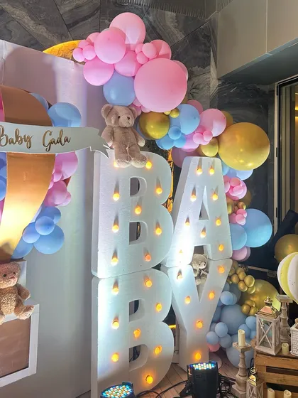 This whimsical baby shower featured large marquee letters, teddy bears nestled in pastel balloon clouds, and a custom hot air balloon prop, creating a dreamy and joyful atmosphere.