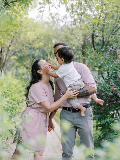 A family playing together in a park. The baby's interaction with his parents is the focus of this sweet shot.