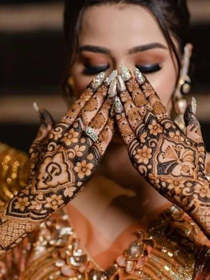 A bride in a moment of prayer or reflection, her hands joined to show the beautiful symmetry of her mehndi design.