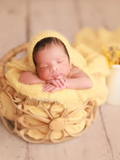 A splash of sunshine. This wider shot shows the full setup, with the baby in a basket and a small white pitcher adding a rustic touch.