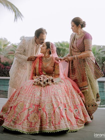 A precious moment between the bride and her parents. The father's kiss on her forehead is a beautiful blessing as she begins her new life.