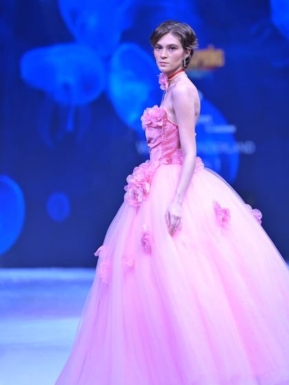 This pink ball gown is a floral fantasy, with a velvet corset bodice adorned with handmade 3D flowers that spill onto the voluminous tulle skirt.