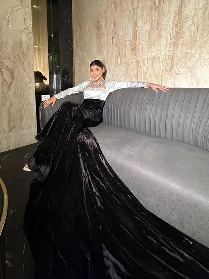 A full-length shot showing the dramatic train of the black velvet skirt. This look is the definition of high-fashion glamour.