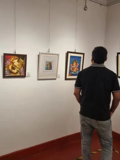 A visitor contemplating the different Ganesha paintings at the exhibition. Each artist brings a unique perspective.
