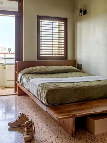 This bedroom in Apartment 5026 features a custom platform bed crafted from a single piece of wood, set against polished terrazzo floors. The design is a nod to the home's mid-century roots, creating a chic and timeless sleeping area.
