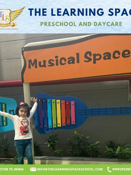 A child proudly stands by our guitar-shaped xylophone. Our unique and playful musical instruments make learning about sound an exciting adventure.