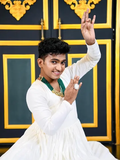 A joyful shot of dancer Niraj Patel in a white traditional outfit. The makeup is fresh and bright, complementing the 'dancing peacock' theme of the shoot.