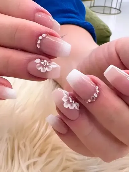 The perfect bridal manicure, combining classic and modern elements. This set features a soft baby boomer ombré on a short coffin shape, accented with delicate 3D flowers and a crescent of sparkling rhinestones for a touch of wedding day magic.