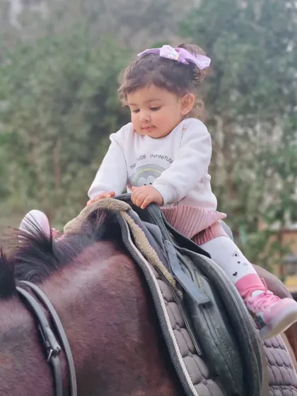 Another angle showing a toddler enjoying her first ride. Our horses' calm demeanor makes these adorable, worry-free photo opportunities possible.