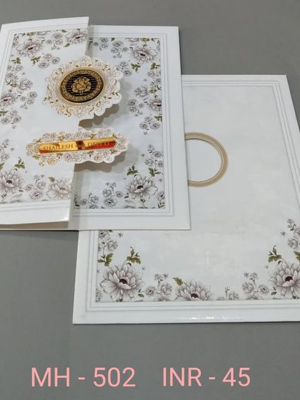 A clean white invitation with a floral print and unique gate-fold closure. The design is modern and interactive, with gold emblems for a touch of luxury.