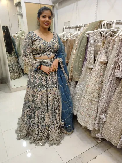 Another angle of the client in the grey-blue lehenga, standing next to the racks to show the variety I offer.