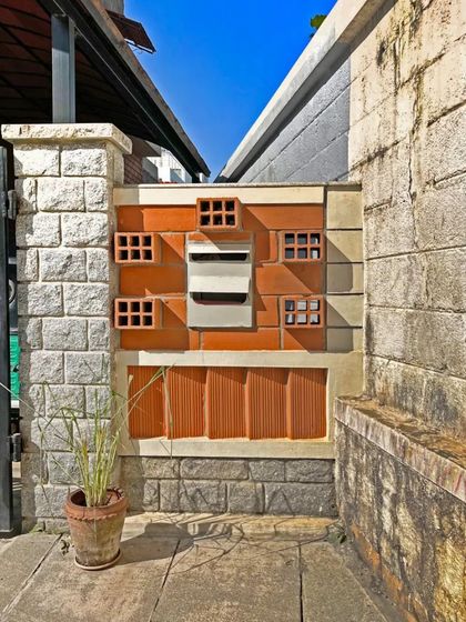 Even small details like a letterbox can reflect an architectural philosophy. Here, hollow terracotta blocks and natural stone are combined to create a functional element that is consistent with the home's material palette.