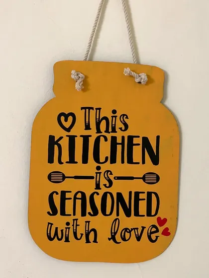 'This kitchen is seasoned with love'. A jar-shaped wall hanging in a cheerful yellow, perfect for adding warmth to your kitchen decor.