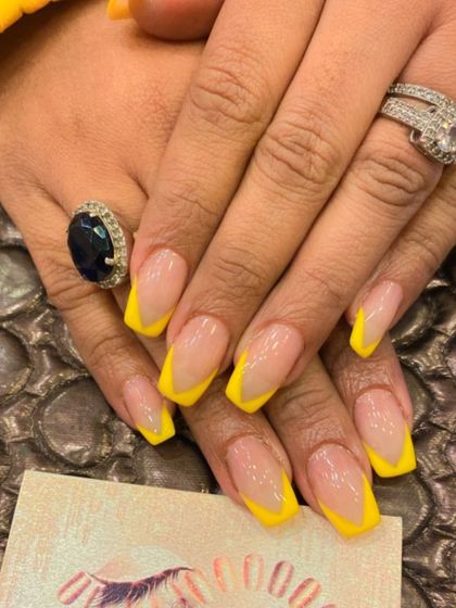 A sunny and bright V-shaped French manicure on square nails. The sheer nude base is paired with cheerful yellow tips for a fun, summery vibe.