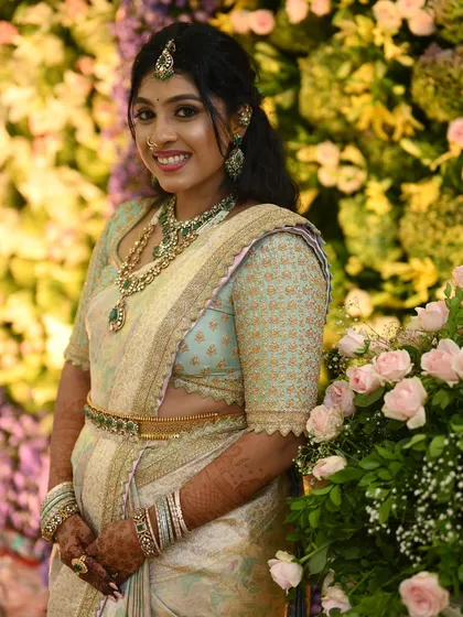 A closer look at the bride's smiling face, highlighting how the soft colors of her custom blouse and saree complement her features and jewelry.