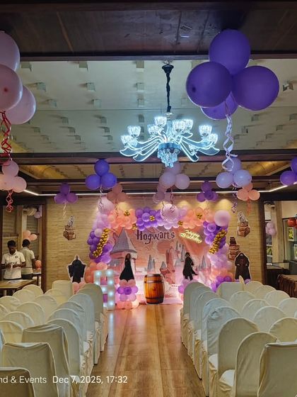 A wide view of the Harry Potter party venue, showing how the stage decor and ceiling balloons create a cohesive look throughout the banquet hall.