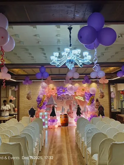 A wide view of the Harry Potter party venue, showing how the stage decor and ceiling balloons create a cohesive look throughout the banquet hall.