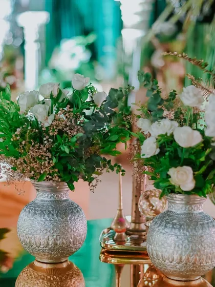 Close-up of a tablescape detail, featuring white roses in ornate silver vases, reflecting the classic and elegant aesthetic of the event.