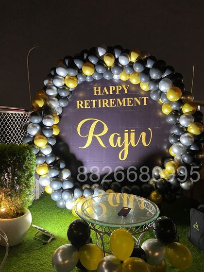 The retirement party decoration seen at night. The lighting highlights the custom backdrop and makes the balloon colors pop, ensuring the setup looks great throughout the event.