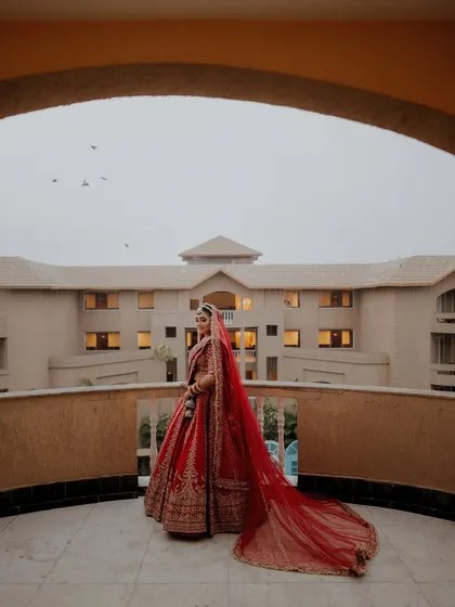A bride's quiet moment of reflection. Prama, looking regal on her balcony in Puri, with her magnificent red veil trailing behind her. I craft these portraits to be as timeless as a painting.