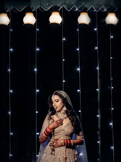 A beautiful portrait of the bride against a curtain of fairy lights, creating a dreamy and magical ambiance for her wedding photos.