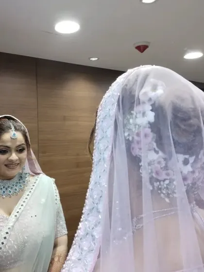 The bride looking in the mirror, showing how the floral bun and veil come together. I ensure the hairstyle is structured enough to support a dupatta while still looking soft.