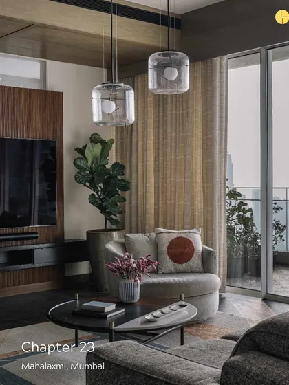 The living area of 'Chapter 23' in Mahalakshmi, where comfort meets purpose. The design uses a mix of plush furniture, modern lighting, and access to an open terrace to create a harmonious living space that resonates with the family's spirit.