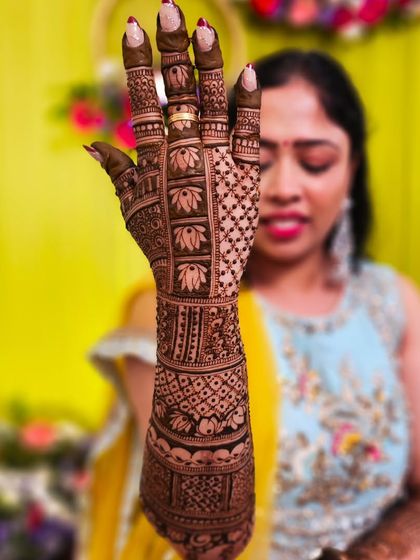 A happy bride showing off her intricate lotus henna, a symbol of purity and beauty.