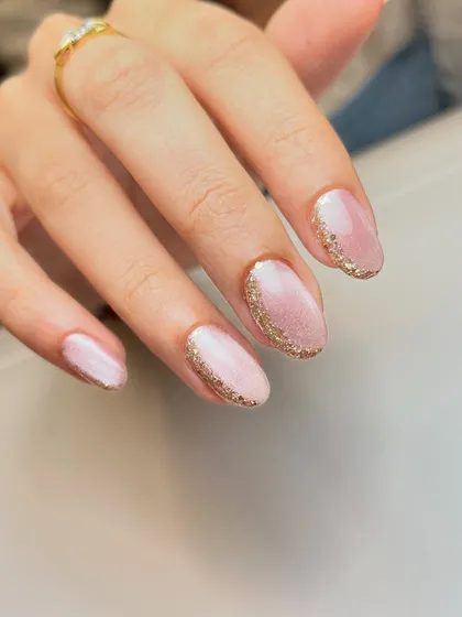 A simple and minimal way to wear glitter. This design features a soft pink cat-eye base with a delicate border of gold glitter around the cuticle.