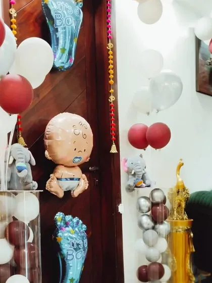Details of a welcome home decoration, featuring baby-themed foil balloons and plush elephants placed on top of balloon pillars.
