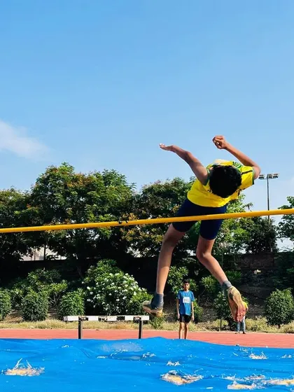 Reaching for the skies. A young athlete clears the bar during a high jump session, demonstrating the technique and courage we nurture.
