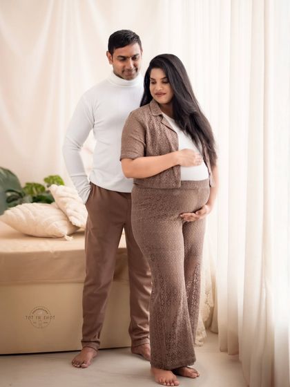 A stylish couple's portrait in coordinated brown and white casual outfits, captured in a soft, naturally lit setting.