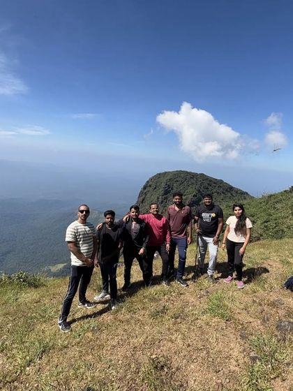 A group photo on the green meadows of the trail, with the peak standing tall in the background.