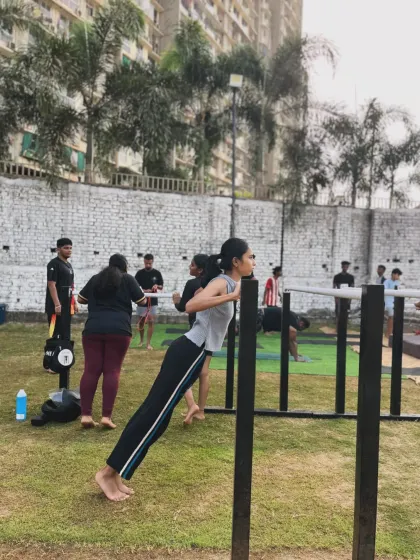 A member practicing her incline push-ups on the outdoor bars. The open-air environment is refreshing and motivating.